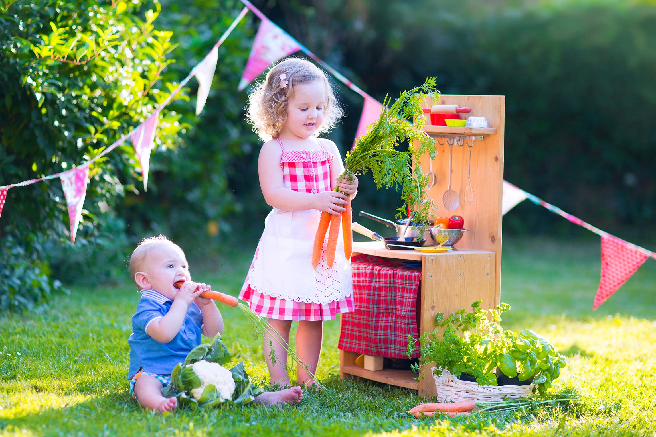 Children eating vegetables outside with toy stove