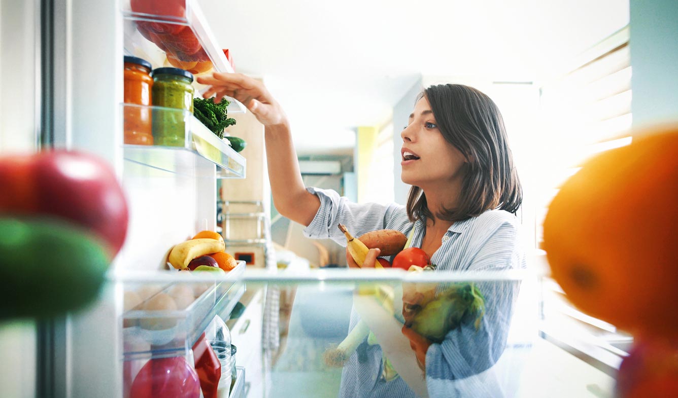 woman picking fruit from refrigerator