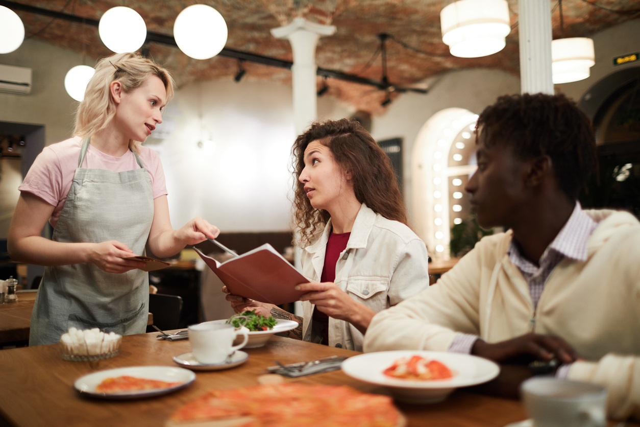 Troubles of going gluten-free: Female restaurant patron talks to a waiter about the menu