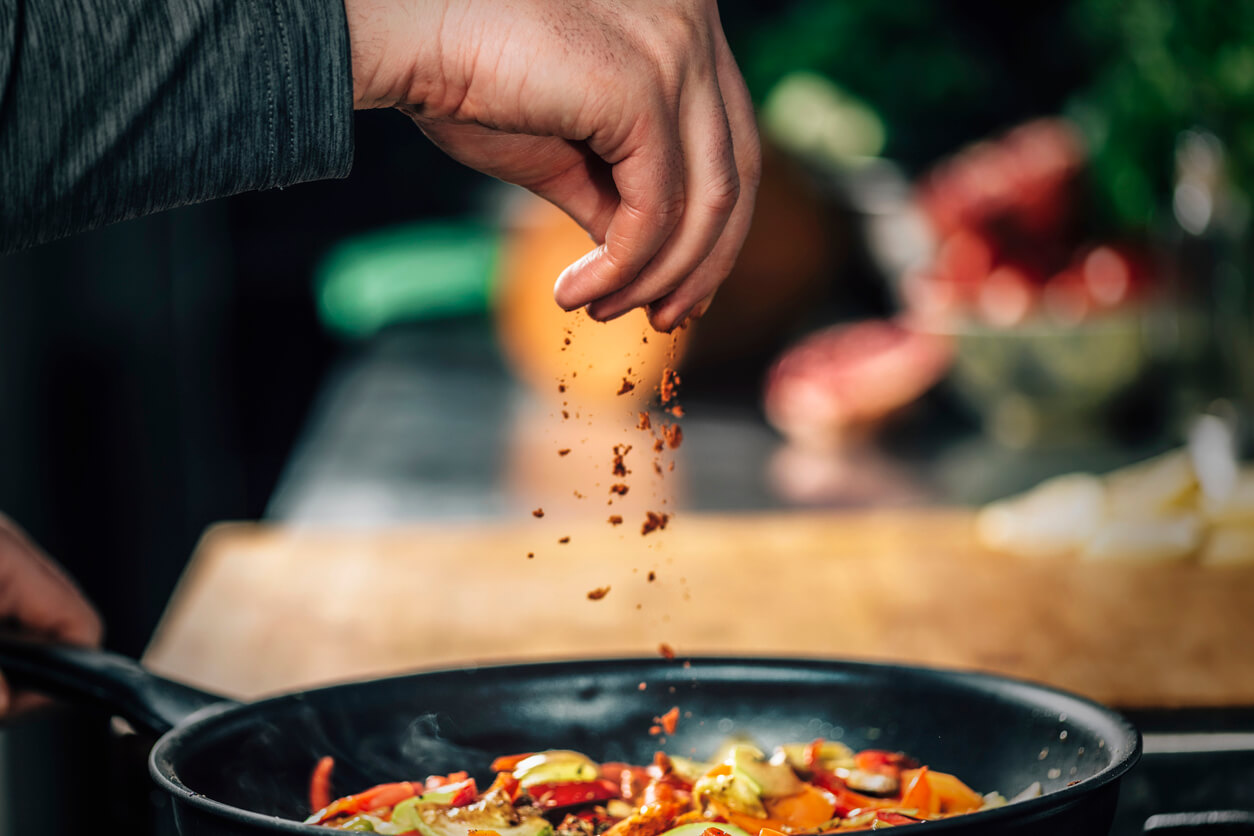 sprinkling ground red chili pepper paprika over sliced vegetables