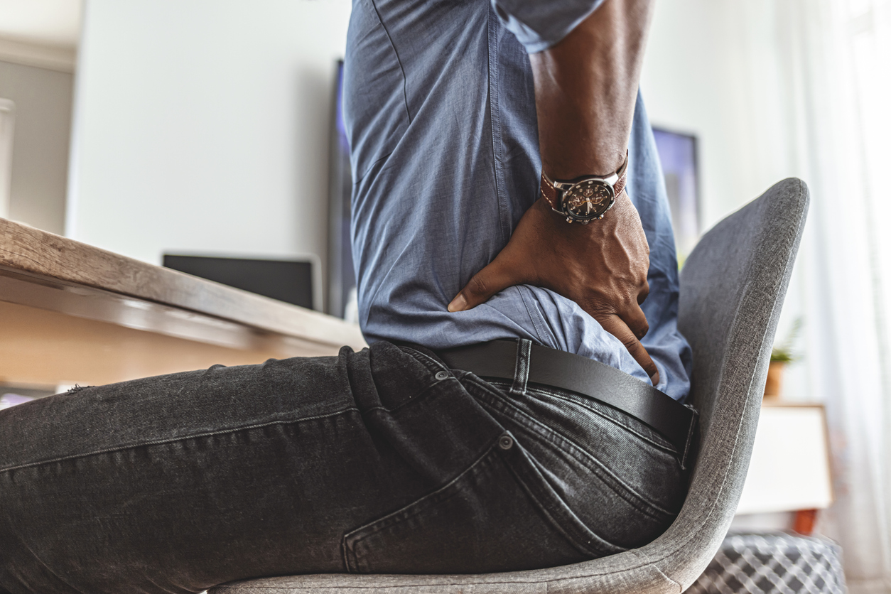 Businessman working sitting at desk feels unhealthy suffers from lower back pain. Damage of intervertebral discs, spinal joints, compression of nerve roots caused by wrong posture and sedentary work.