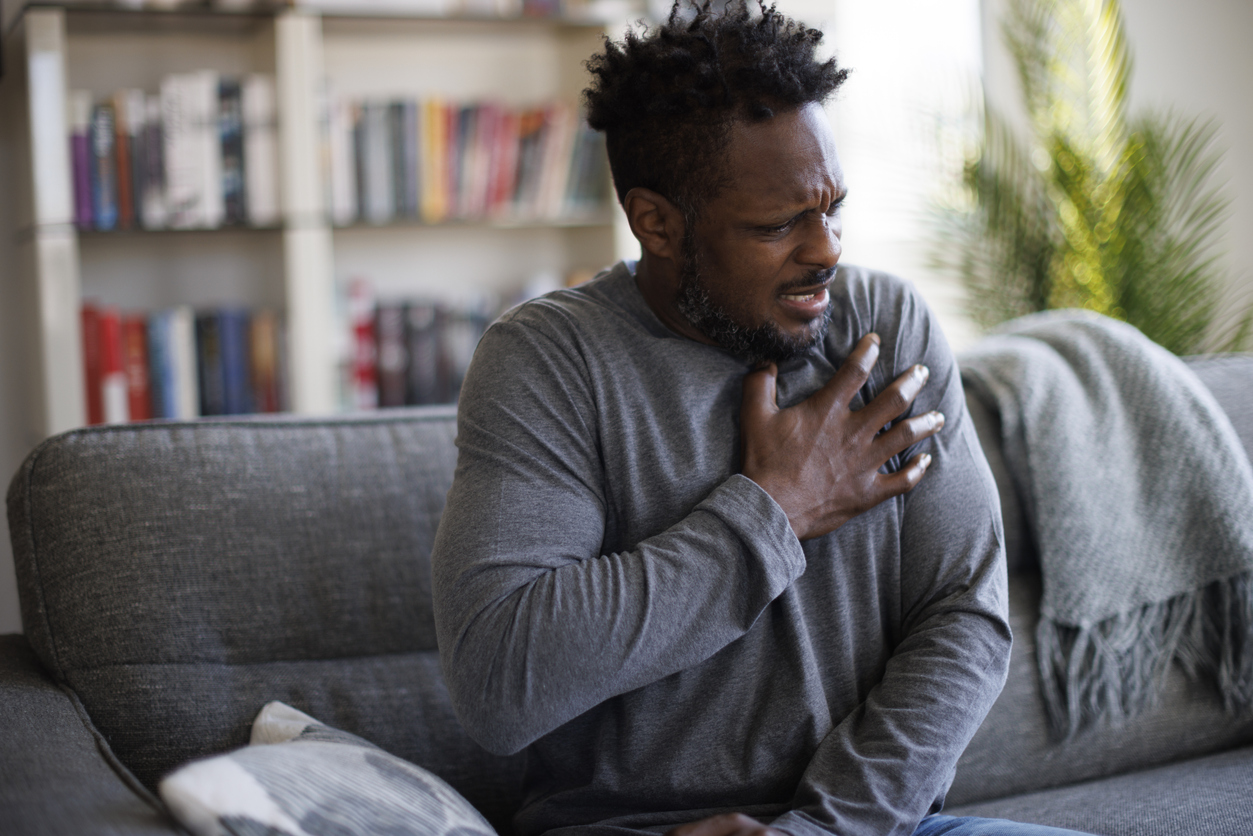 Close-up photo of a stressed man who is suffering from a chest pain and touching his heart area