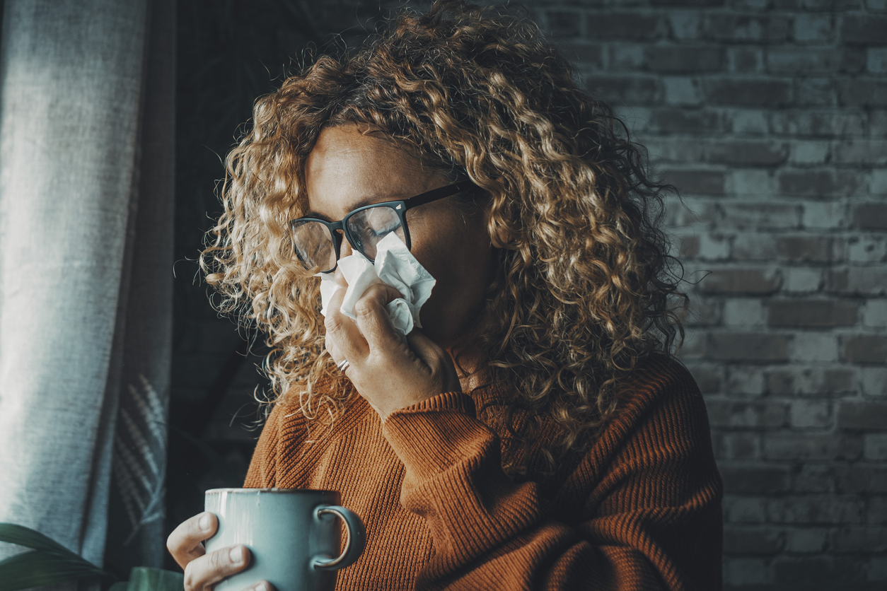 One woman sneezing nose with fever and influenza virus health disease. Flu and cold for winter temperature at home. People suffering for unhealthy bad condition indoor. Female with paper towels