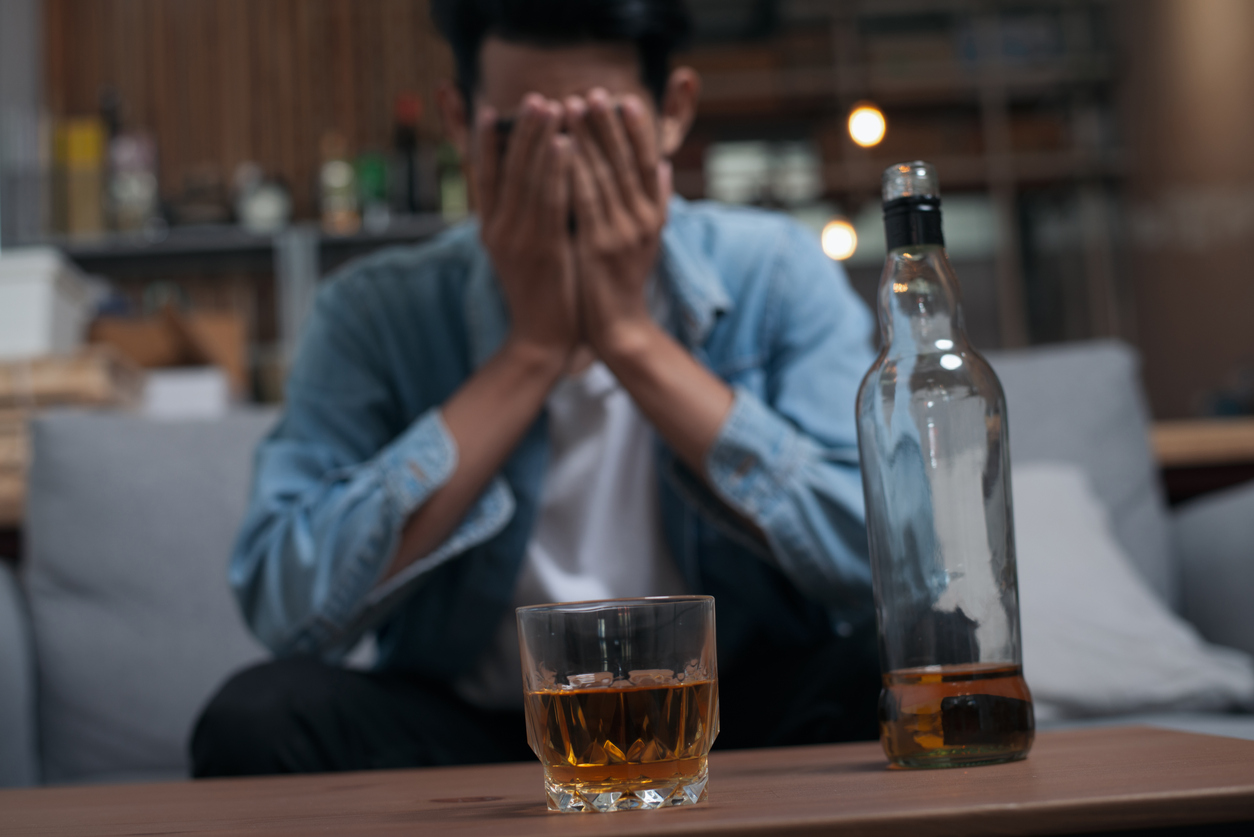 Alcoholism or Alcoholic concept : Close up young Asian guy feeling depressed drinking alcohol alone in pub or bar because life problem or stress.