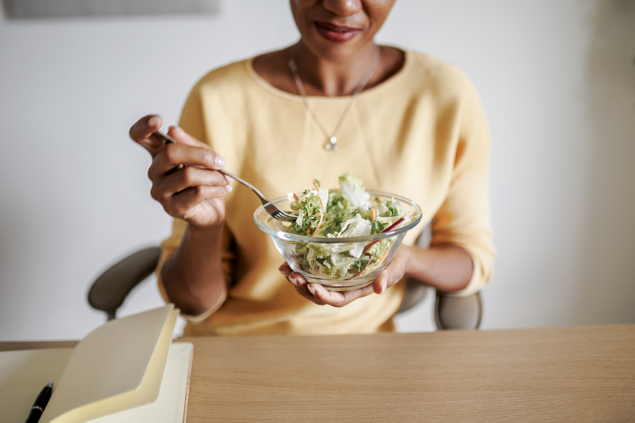 Mid adult black woman having snack at home office